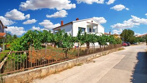 A residential area with a white house, a vineyard, and a clear blue sky. - Apartment 1468 (Fazana)