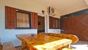 A wooden dining table with benches, a window with shutters, and an air conditioning unit. - Apartment 1468 (Fazana)