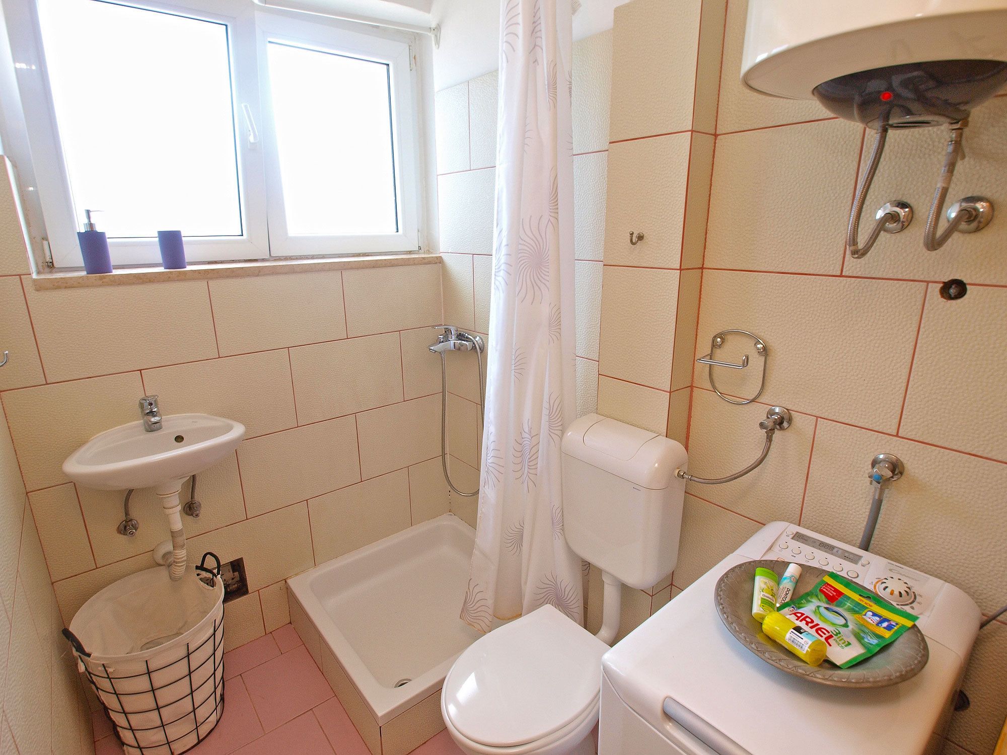 A bathroom with a bathtub, toilet, sink, and a window.