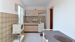 A compact kitchen with a microwave, coffee maker, and a small refrigerator. There is a sink and a window providing natural light. - Apartment 1471 (Labin)