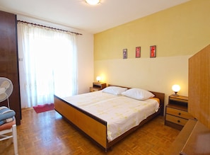 A bedroom with a wooden bed, two bedside tables with lamps, a chair, and a window with curtains. - Apartment 1471 (Labin)
