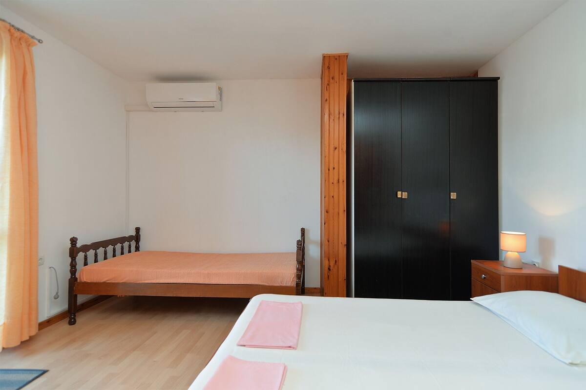 Une chambre à coucher comprenant un lit, une armoire, une table de chevet et un appareil de climatisation.