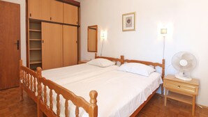 A bedroom with a wooden bed, a bedside table, a nightstand, a wardrobe, a mirror, and a wall-mounted fan. - Apartment 1471 (Labin)