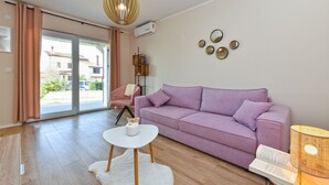 Una sala moderna con un sofá morado, una mesa de centro blanca y una lámpara colgante original.