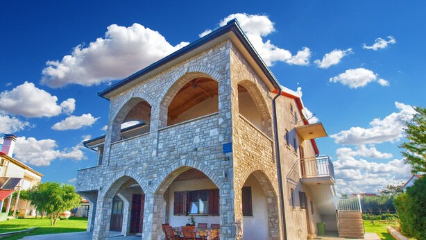 Un edificio de piedra con un patio central, ventanas de arco y un balcón.