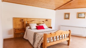Een houten bed met hoofdbord, nachtkastje en bijzettafeltje.