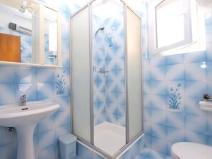 A bathroom with a glass-enclosed shower, a sink, and a toilet. - Apartment 1482 (Medulin)
