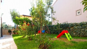 Un giardino con altalena, scivolo e un vialetto in pietra.