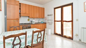 Una cocina con armarios de madera, estufa a gas, cafetera y mesa de comedor con sillas.