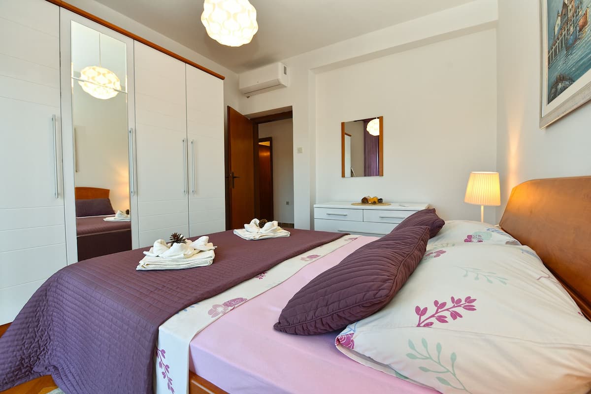 A hotel room with a large bed, a dresser, a mirror, and a wardrobe.