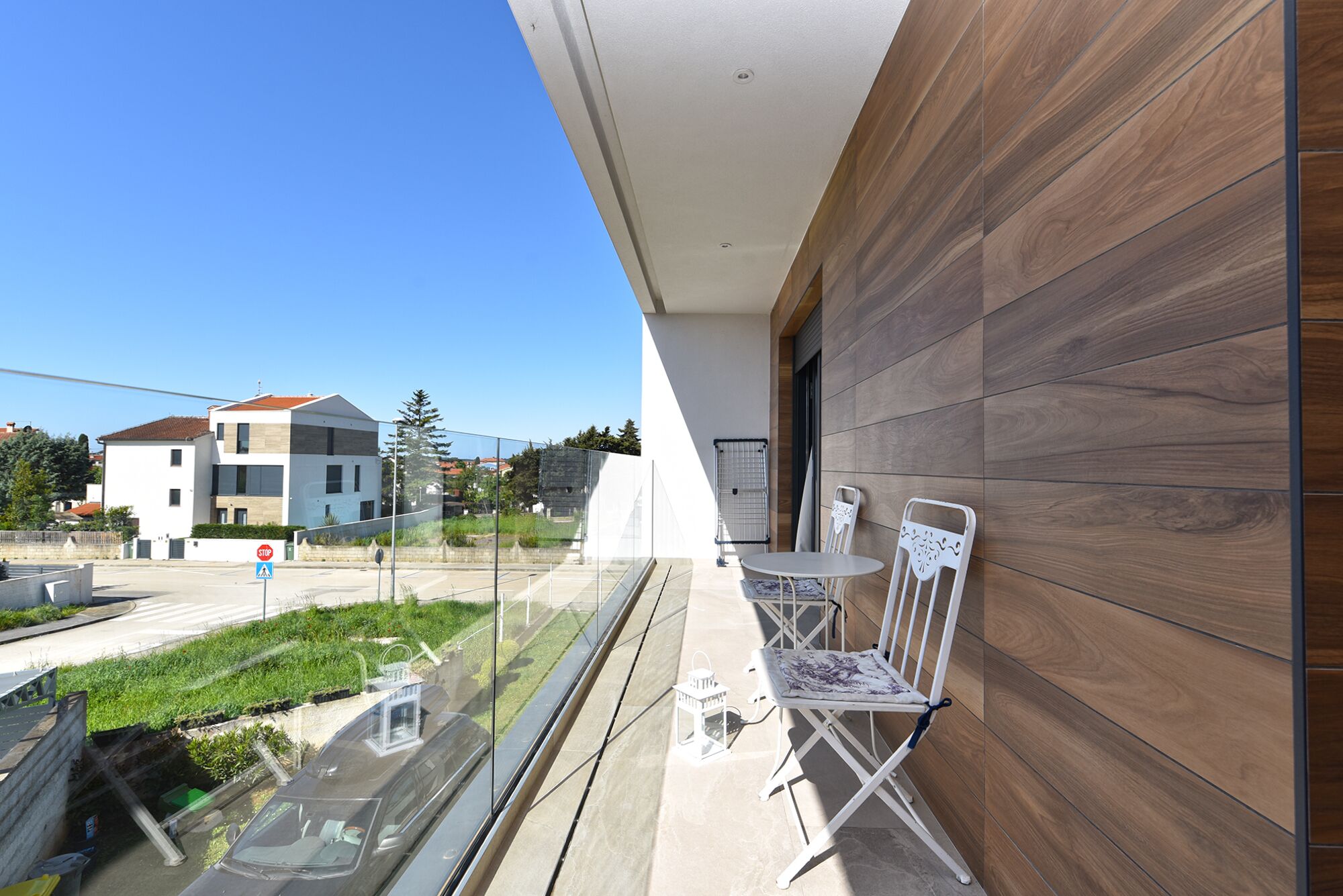 Ein Balkon mit Tisch und Stühlen, Blick auf die Straße und ein Gebäude im Hintergrund.