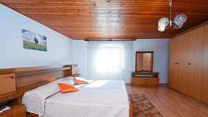 A bedroom with a wooden bed, a nightstand, a dresser, a mirror, and a ceiling fan. - Apartment 1492 (Barban)