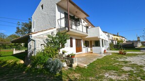 A two-story house with a stone facade, a balcony, and a small garden area with potted plants. - Apartment 1492 (Barban)