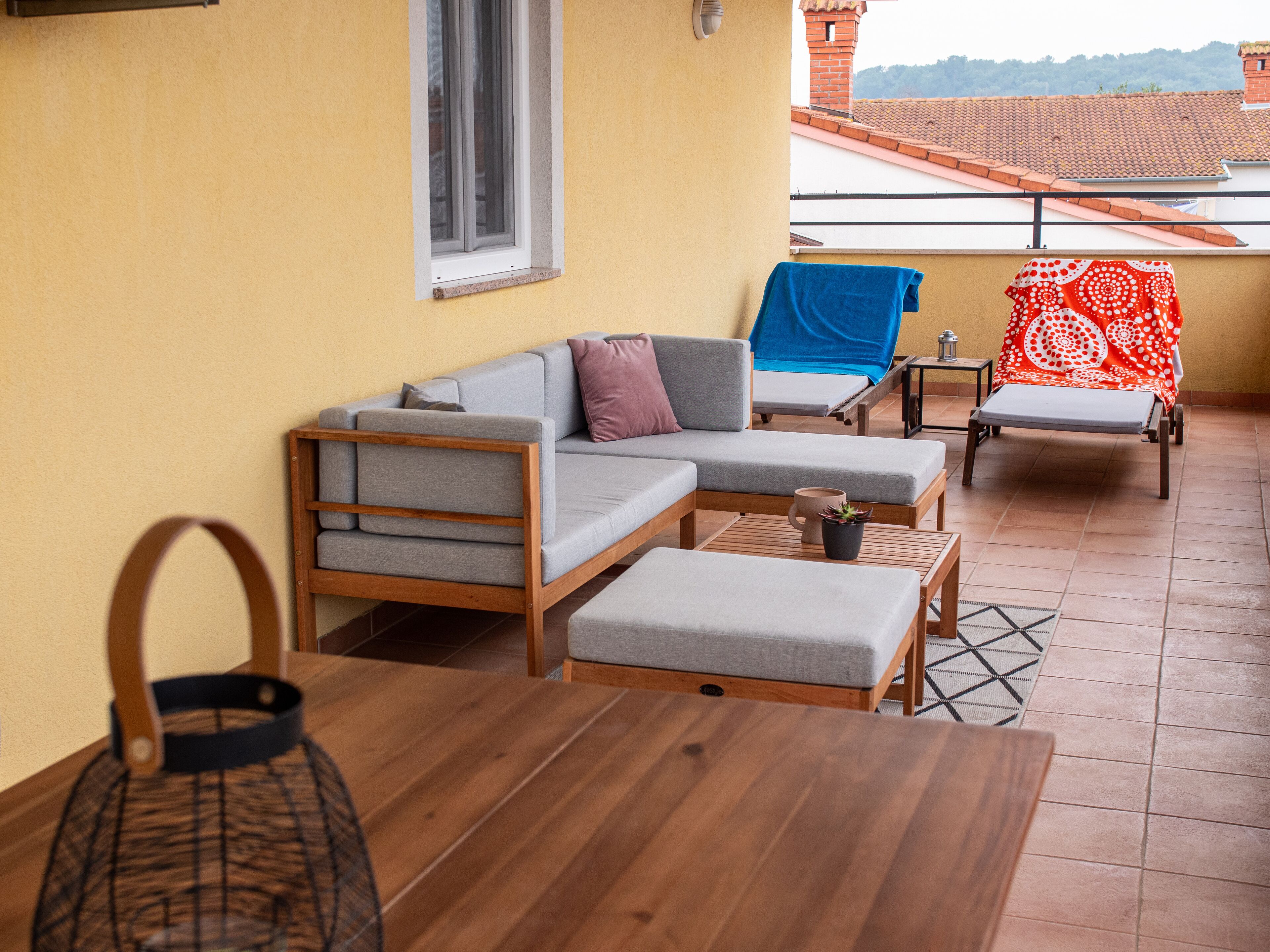 A balcony with a sofa, a chair, a small table, and a potted plant.