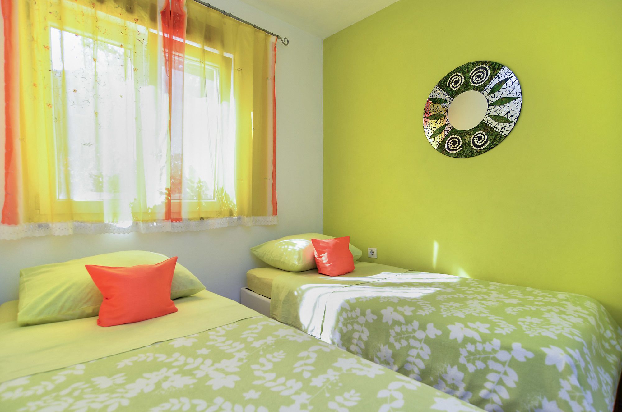Una habitación con dos camas, una ventana con cortinas y un adorno en la pared.