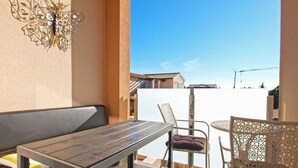 A balcony with a table, chairs, and a decorative metal piece. - Apartment 1507 (Fazana)