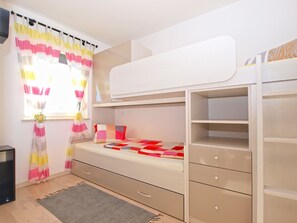 A bunk bed with a desk and drawers, a window with curtains, and a small rug on the floor. - Apartment 1507 (Fazana)