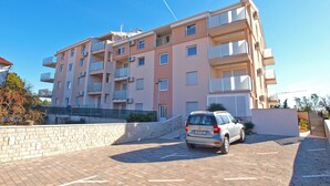 A multi-story apartment building with balconies, a parking area, and a clear blue sky. - Apartment 1507 (Fazana)