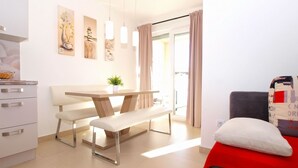 A modern kitchen with a dining area, a bench, and a red sofa. - Apartment 1507 (Fazana)