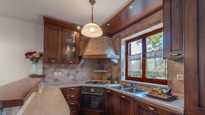 A kitchen with dark wooden cabinets, a built-in oven, a sink, and a window with a view. - Apartment 1510 (Marcana)