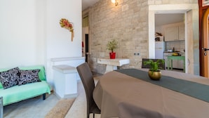 A cozy living area with a sofa, a dining table, and a kitchen visible through an open doorway. - Apartment 1510 (Marcana)