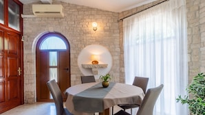 A dining area with a round table, chairs, a potted plant, and a stone wall. - Apartment 1510 (Marcana)