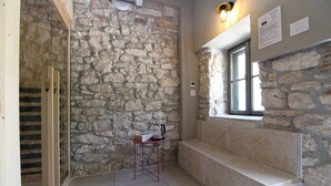 A stone-walled bathroom with a bench, a window, and a small table with a kettle. - House 1529 (Medulin)