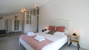 A bedroom with a large bed, white walls, a wooden floor, a white wardrobe, and a door leading to another room. - House 1529 (Medulin)