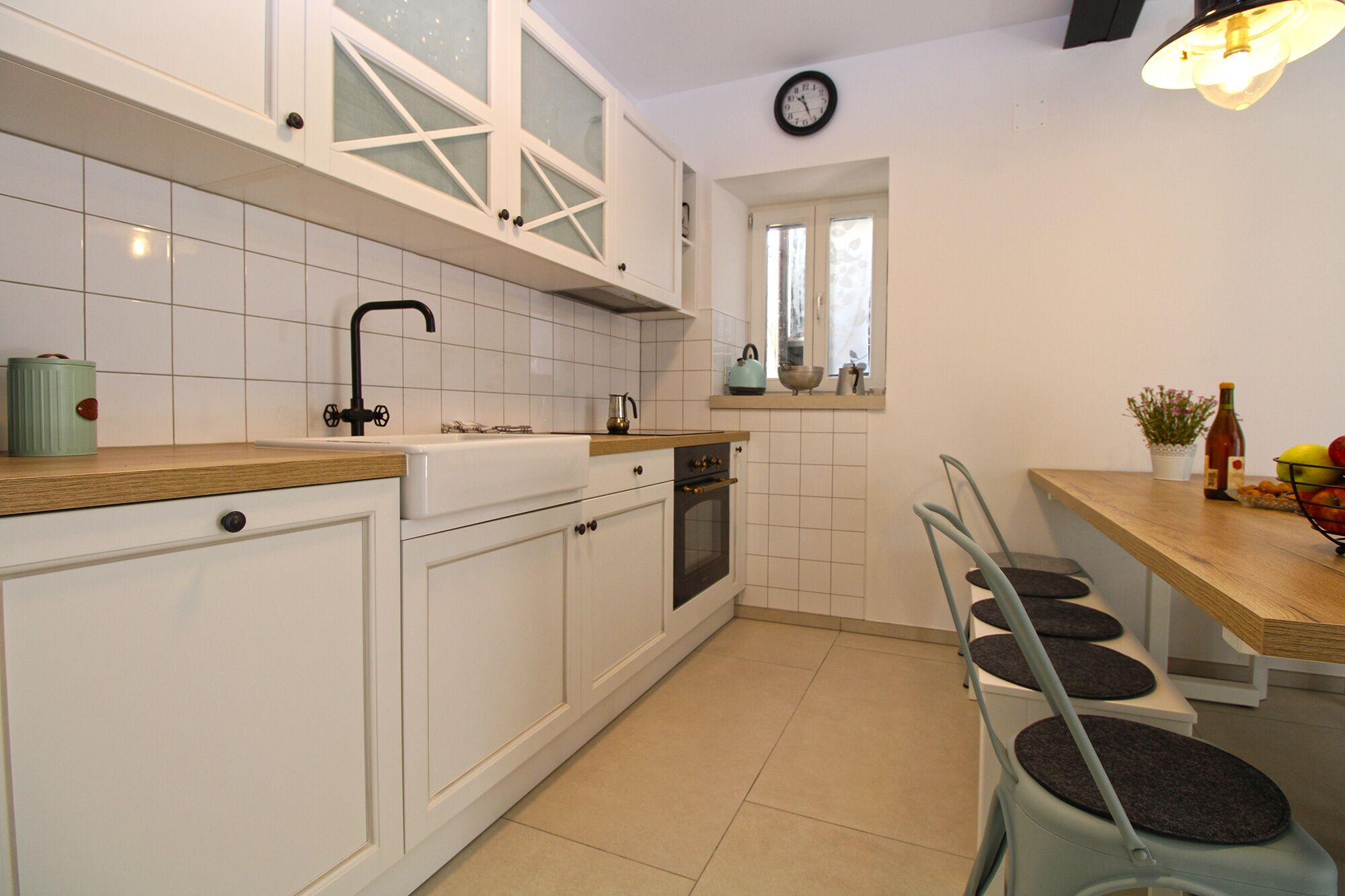 A kitchen with white cabinets, a sink, a stove, and a window with curtains.