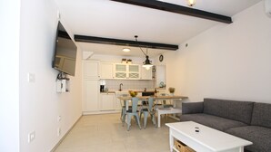 A compact living space with a kitchenette, a dining area with mismatched chairs, and a grey sofa. - House 1529 (Medulin)