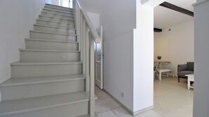A staircase leading to a room with a dining area and a gray sofa. - House 1529 (Medulin)