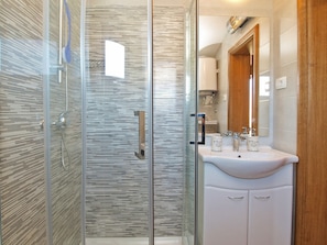 A modern bathroom with a glass-enclosed shower, a white sink, and a wooden door. - Apartment 1536 (Vodnjan)