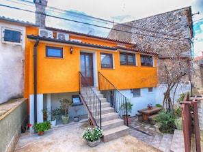 A two-story building with a bright orange facade, a wooden staircase, and potted plants. - Apartment 1536 (Vodnjan)