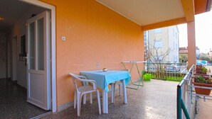 A balcony with a table and chairs, a door leading inside, and a view of the street and buildings. - Apartment 1539 (Fazana)