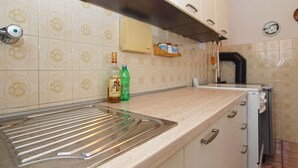 A kitchen with a stainless steel sink, a toaster, and a shelf with jars. - Apartment 1539 (Fazana)