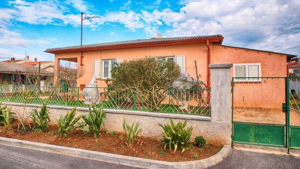 A house with a red roof, a garden with plants, and a green fence. - Apartment 1539 (Fazana)
