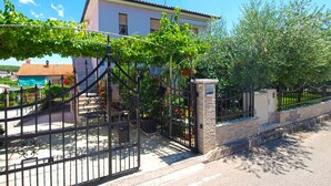 A house with a gated entrance, a stone wall, and a metal gate. - Apartment 1540 (Pula)