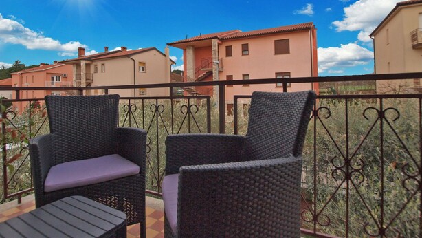 A balcony with wicker chairs and a view of neighboring houses. - Apartment 1540 (Pula)