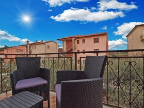 A balcony with wicker chairs and a view of neighboring houses. - Apartment 1540 (Pula)