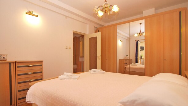 Ein Schlafzimmer mit einem großen Bett, einem Holzschrank und einem Spiegel.
