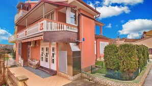 Ein zweigeschossiges Haus mit Balkon, kleinem Garten und Satellitenschüssel.