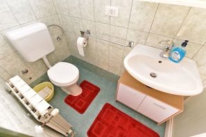 A bathroom with a toilet, sink, and a shower area. - Apartment 1550 (Rovinj)