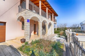 A stone building with a balcony, a wooden door, and a garden with yellow flowers. - Apartment 1551 (Rovinj)
