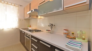 Een moderne keuken met een gasfornuis, roestvrijstalen apparatuur en houten kasten.