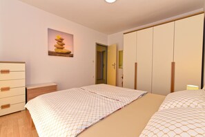 A bedroom with a bed, a dresser, a mirror, and a painting of stones. - Apartment 1551 (Rovinj)