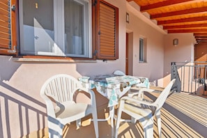 A balcony with a table and chairs, wooden shutters, and a view of the surrounding area. - Apartment 1551 (Rovinj)