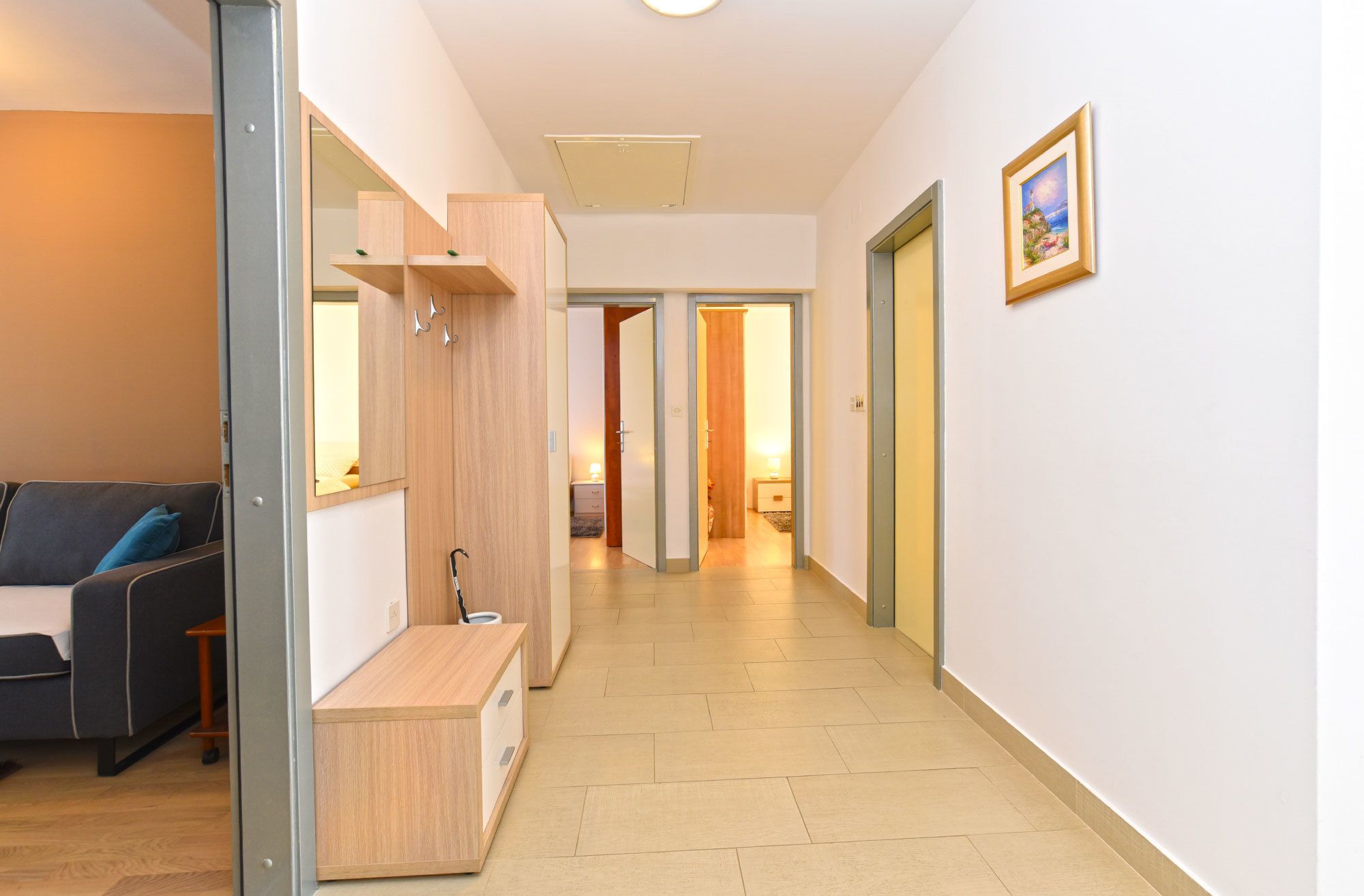A hallway with a sofa, a wooden bench, and a wardrobe. There are doors leading to other rooms.