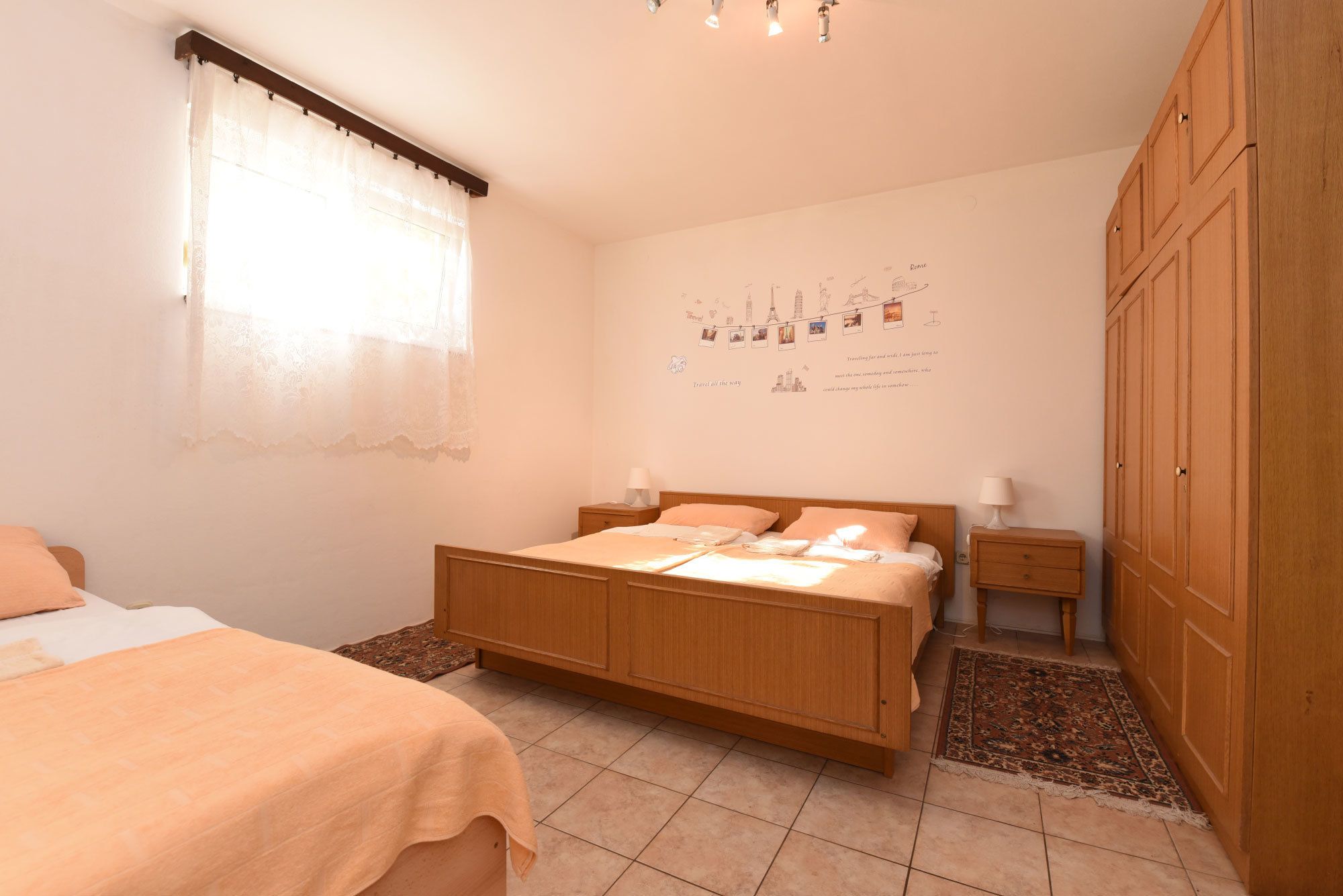 Un dormitorio con una cama de madera, una mesita de noche, un armario y una pared decorada con motivos de viaje.