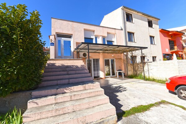 A two-story building with a covered entrance and a red car parked nearby. - Apartment 1562 (Pula)