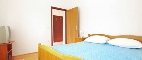 A bedroom with a wooden bed, a nightstand, a desk with a lamp, and a wardrobe.